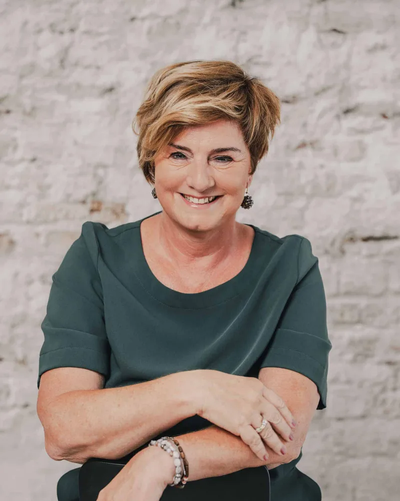 Daphne Wijnstok, zittend op een kruk, lachend